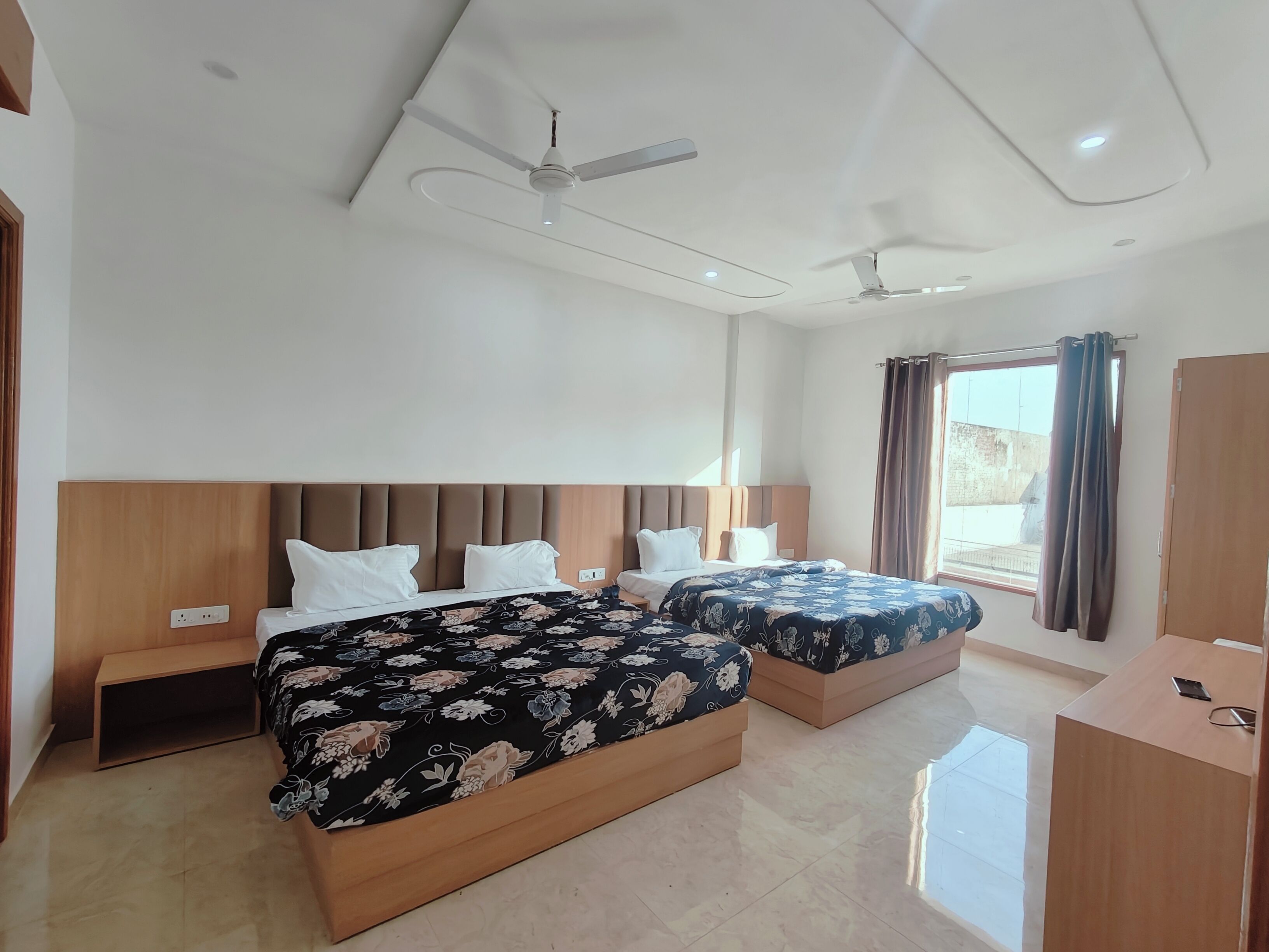 Una habitación de hotel con dos camas, un ventilador de techo y un escritorio.