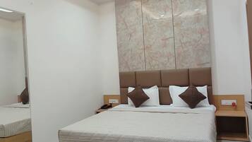 A modern bedroom with a large bed, a ceiling fan, recessed lighting, and a marble-patterned wall.
