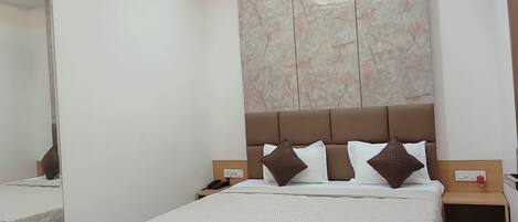 A modern bedroom with a large bed, a ceiling fan, recessed lighting, and a marble-patterned wall.