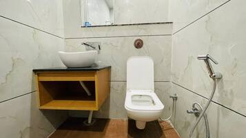 Un baño con inodoro blanco, lavabo con encimera de mármol y ducha.