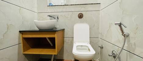 A bathroom with a white toilet, a sink with a marble countertop, and a shower.