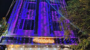 A building with a neon sign reading "Pilgrim" and multiple windows illuminated with purple and blue lights. - Hotel Pilgrim Near Golden Temple (Amritsar)