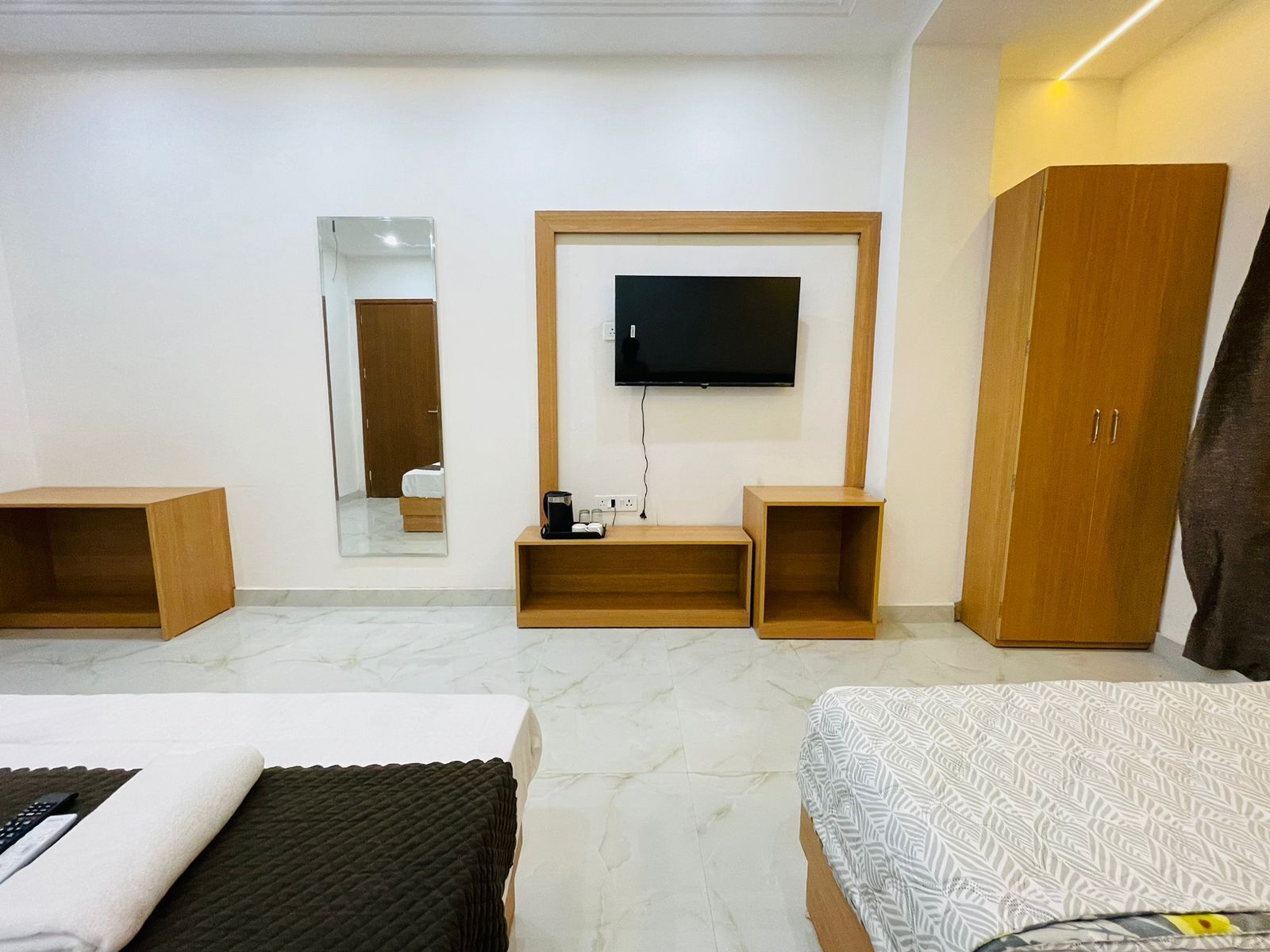 Habitación de hotel con cama, televisión montada en la pared, armario y espejo.