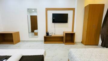 A hotel room with a bed, a TV mounted on the wall, a wardrobe, and a mirror.