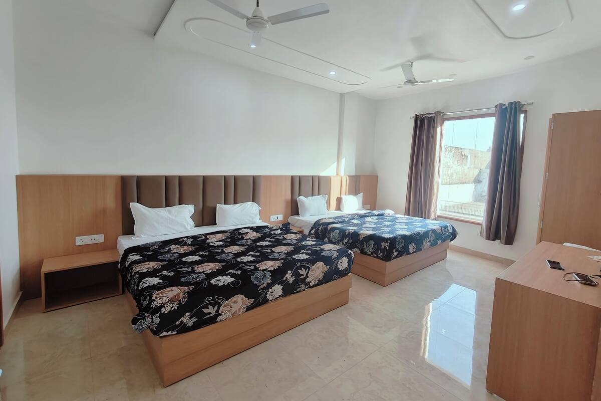 A hotel room with two beds, a desk, and a ceiling fan.