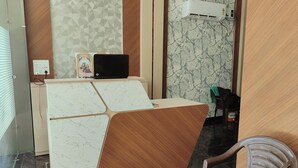 A reception area with a marble-patterned desk, a black monitor, and a wall-mounted air conditioner. - Hotel Pilgrim Near Golden Temple (Amritsar)
