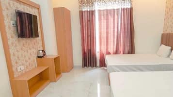 Un dormitorio con dos camas, un ventilador de techo, un televisor montado en la pared y una ventana con cortinas.