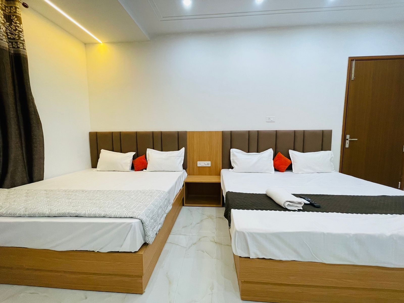 A hotel room with two single beds, a wooden headboard, white bedding, and a door.