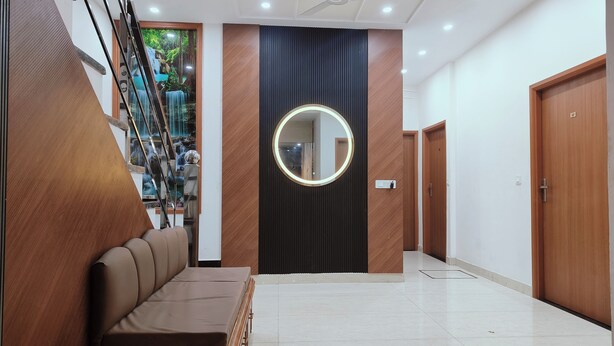 A modern hallway with a wooden bench, a round mirror, and a ceiling fan. - Hotel Pilgrim Near Golden Temple (Amritsar)