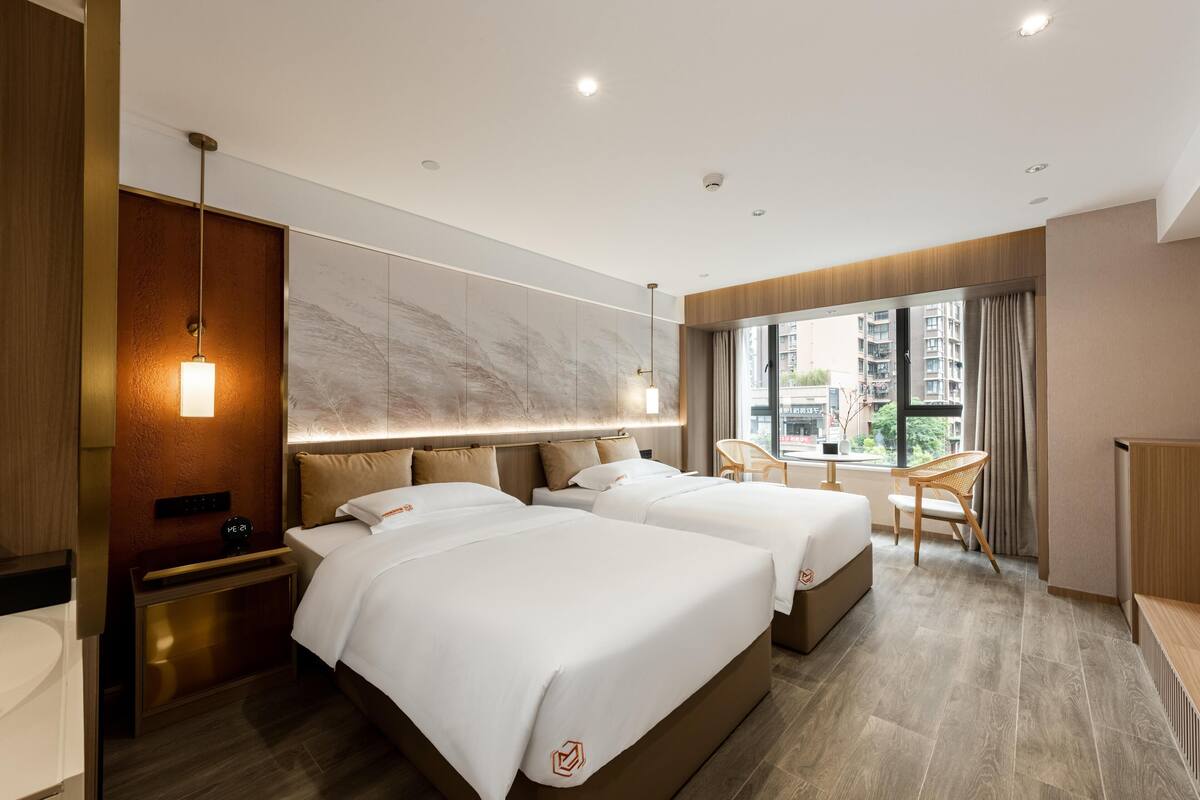 Habitación de hotel con dos camas, un escritorio y vistas a la ciudad.