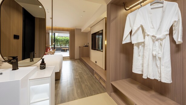 A modern hotel bathroom with a large mirror, a sink, a robe rack, and a television. - Leshan Manfu Hotel (Leshan)