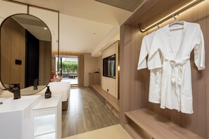 A modern hotel bathroom with a large mirror, a sink, a robe rack, and a television. - Leshan Manfu Hotel (Leshan)