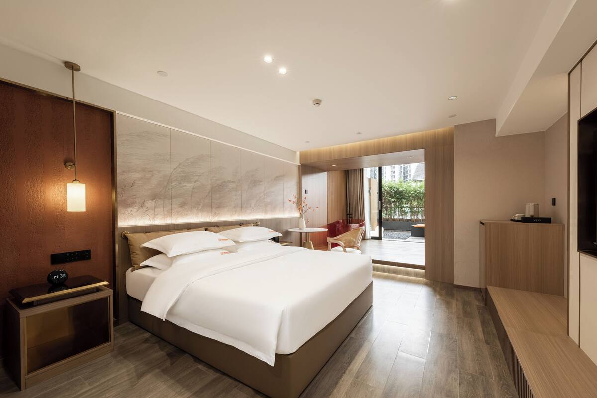 Una habitación de hotel moderna con una cama grande, una mesita de noche y un televisor.