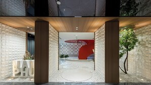 A modern lobby with a geometric wall design, a central circular seating area, and a visible reception desk. - Leshan Manfu Hotel (Leshan)