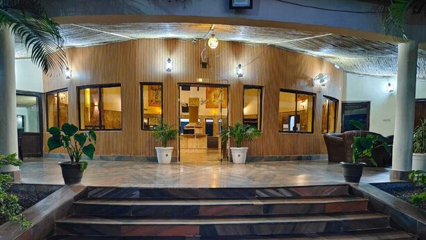 Fachada de hotel de madera, con grandes ventanales y una escalera que conduce a la recepción.