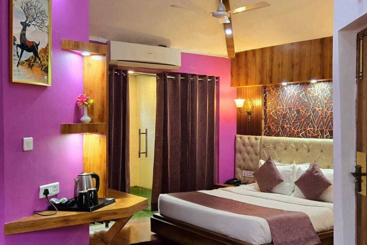 Un dormitorio moderno con una cama grande, una mesita de noche con hervidor, aire acondicionado en la pared y un panel decorativo.