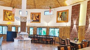 Un comedor amplio con una mesa redonda central, rodeada de sillas, y un ventanal que ofrece vistas al exterior.