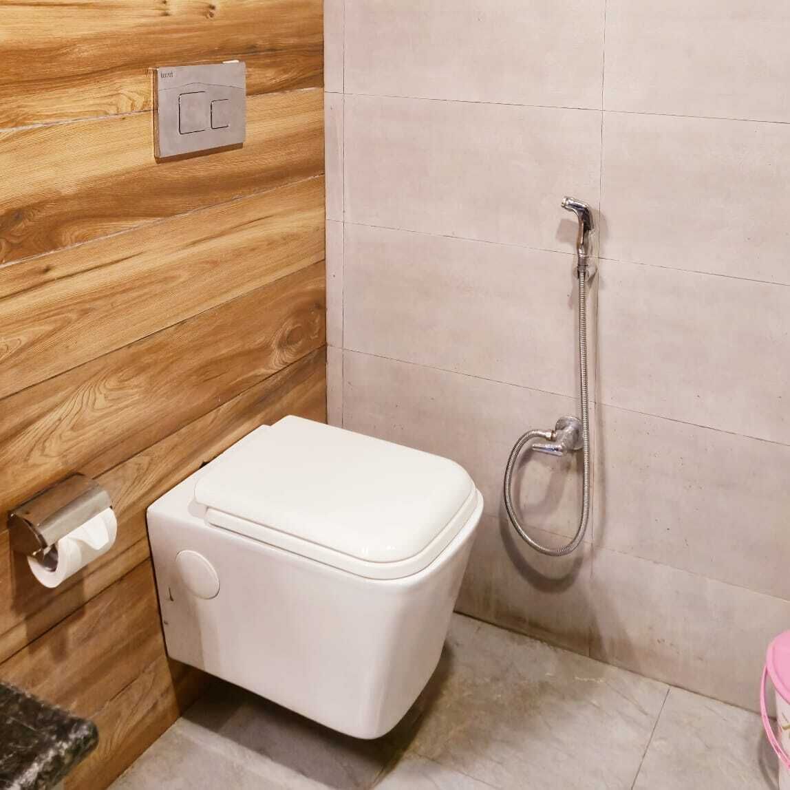 Un baño pequeño con inodoro, ducha y pared de madera.