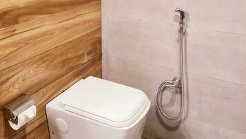 Un baño pequeño con inodoro, ducha y pared de madera.