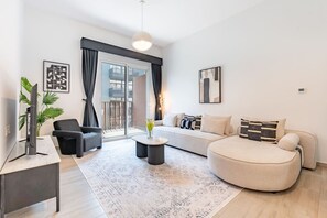 A modern living room with a sofa, armchair, coffee table, and a TV on a stand.