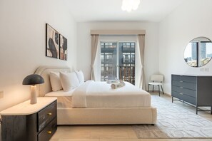 A bedroom with a bed, bedside table, lamp, dresser, and a view of the city through large windows. - Contemporary 1Bedroom Escape in Eaton Place (Dubai)