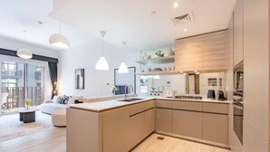 A modern kitchen with a central island, built-in appliances, and pendant lighting. - Contemporary 1Bedroom Escape in Eaton Place (Dubai)