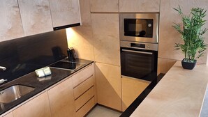 A modern kitchen with wooden cabinetry, a built-in microwave, oven, and a sink. - Anémona Apartments GR FL – Your Home in Matosinhos, Where City Meets the Sea (Matosinhos)