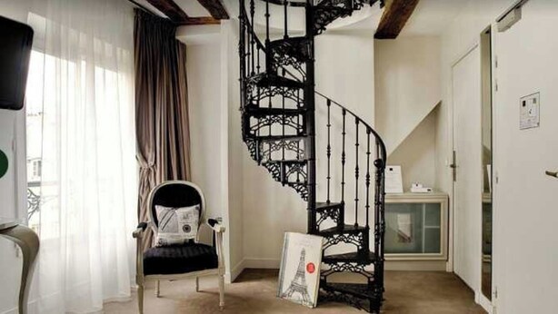 Ein Zimmer mit Wendeltreppe, einem Sessel, einem Bilderrahmen und einem Schrank.
