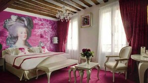 Ein Schlafzimmer mit einem Bett, einem Sessel, einem Tisch, einer Chandelier und einem Wandbild.