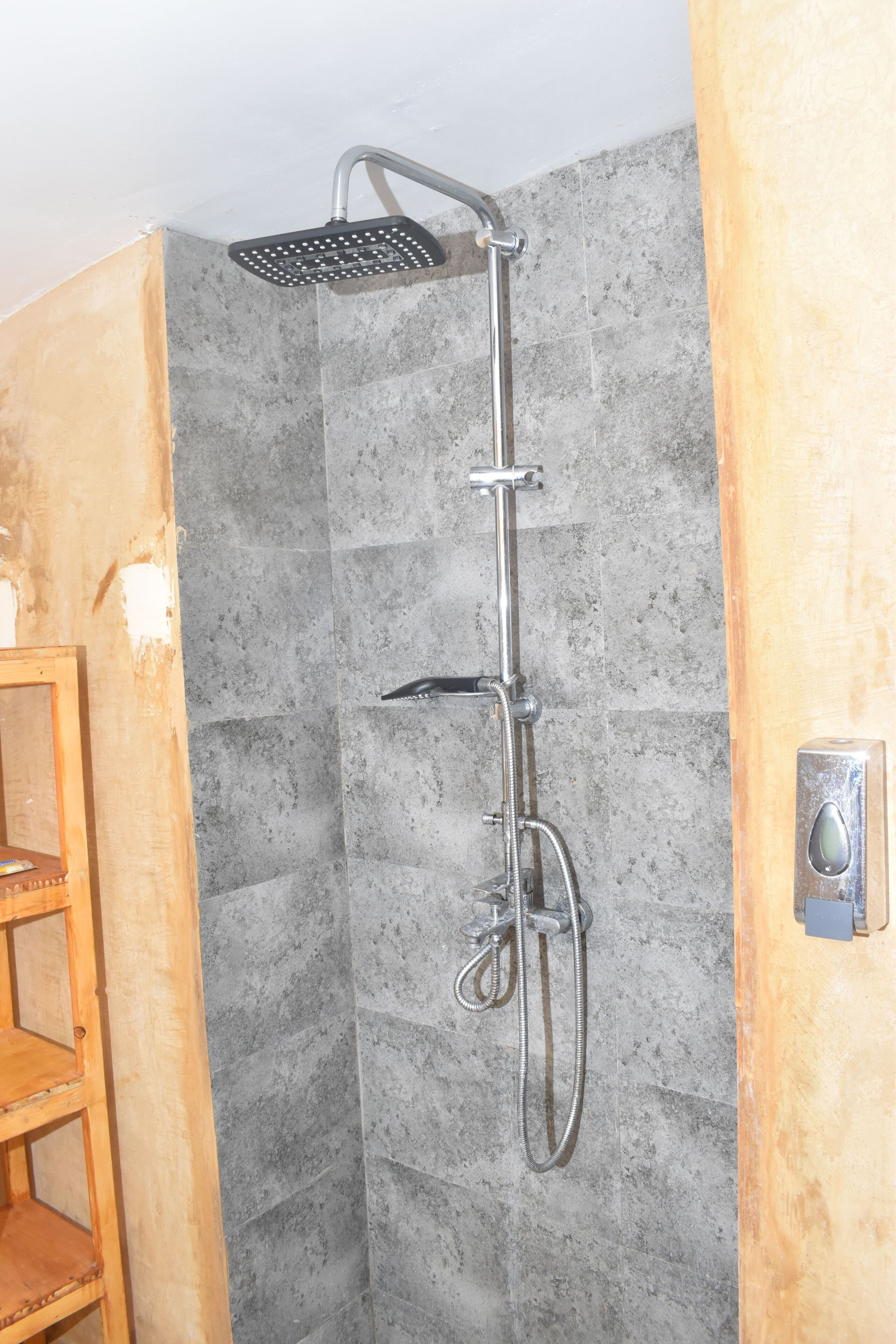 Une douche équipée d’un pommeau de douche à main et d’un flexible à main.