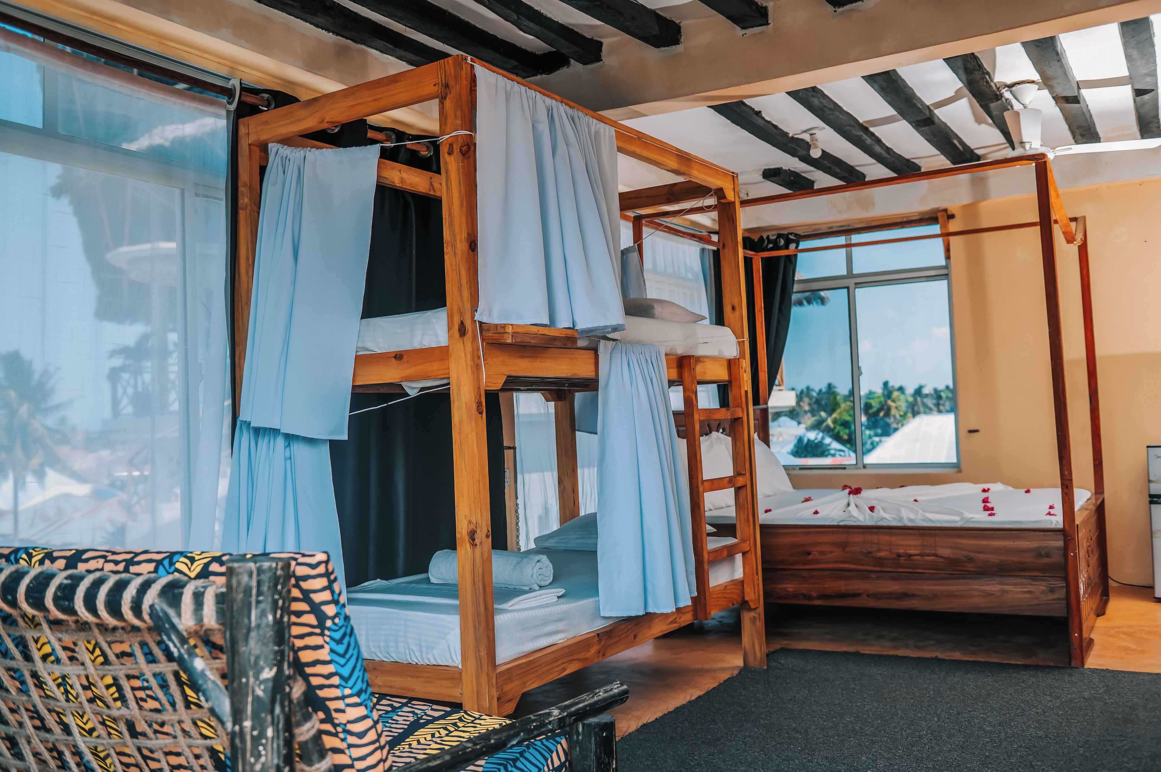 Ein Zimmer mit Etagenbett, Einzelbett und Sessel mit gemustertem Kissen.
