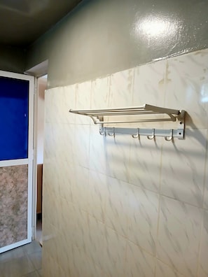 Quarto com um porta-toalhas de metal fixado em uma parede com padrão marmorizado.