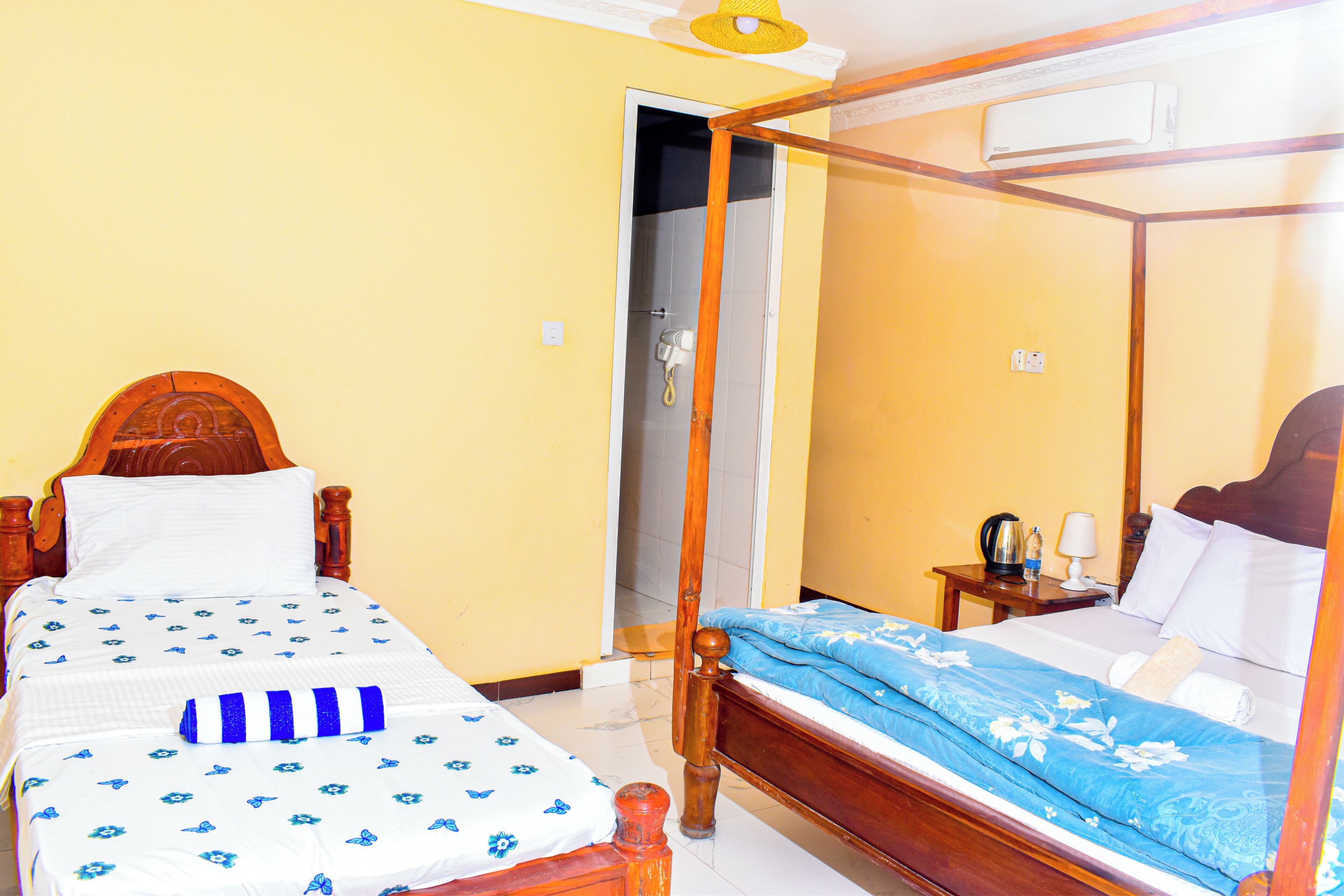 A room with a wooden bed, a wooden nightstand, a mirror, and a door leading to a bathroom.