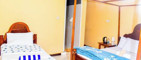 A room with a wooden bed, a wooden nightstand, a mirror, and a door leading to a bathroom.