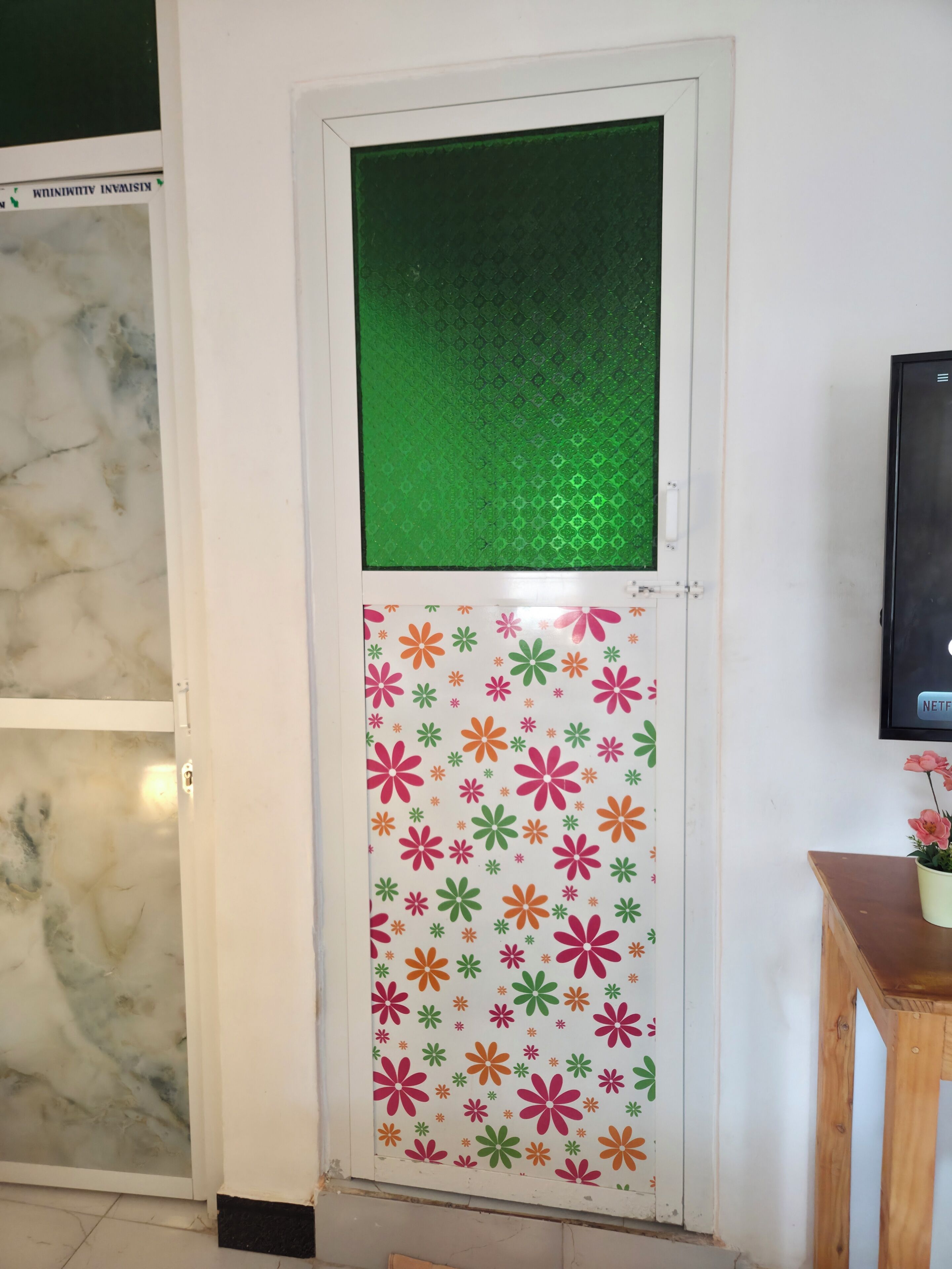 Puerta con un panel de vidrio texturizado color verde y una sección inferior con estampado floral.