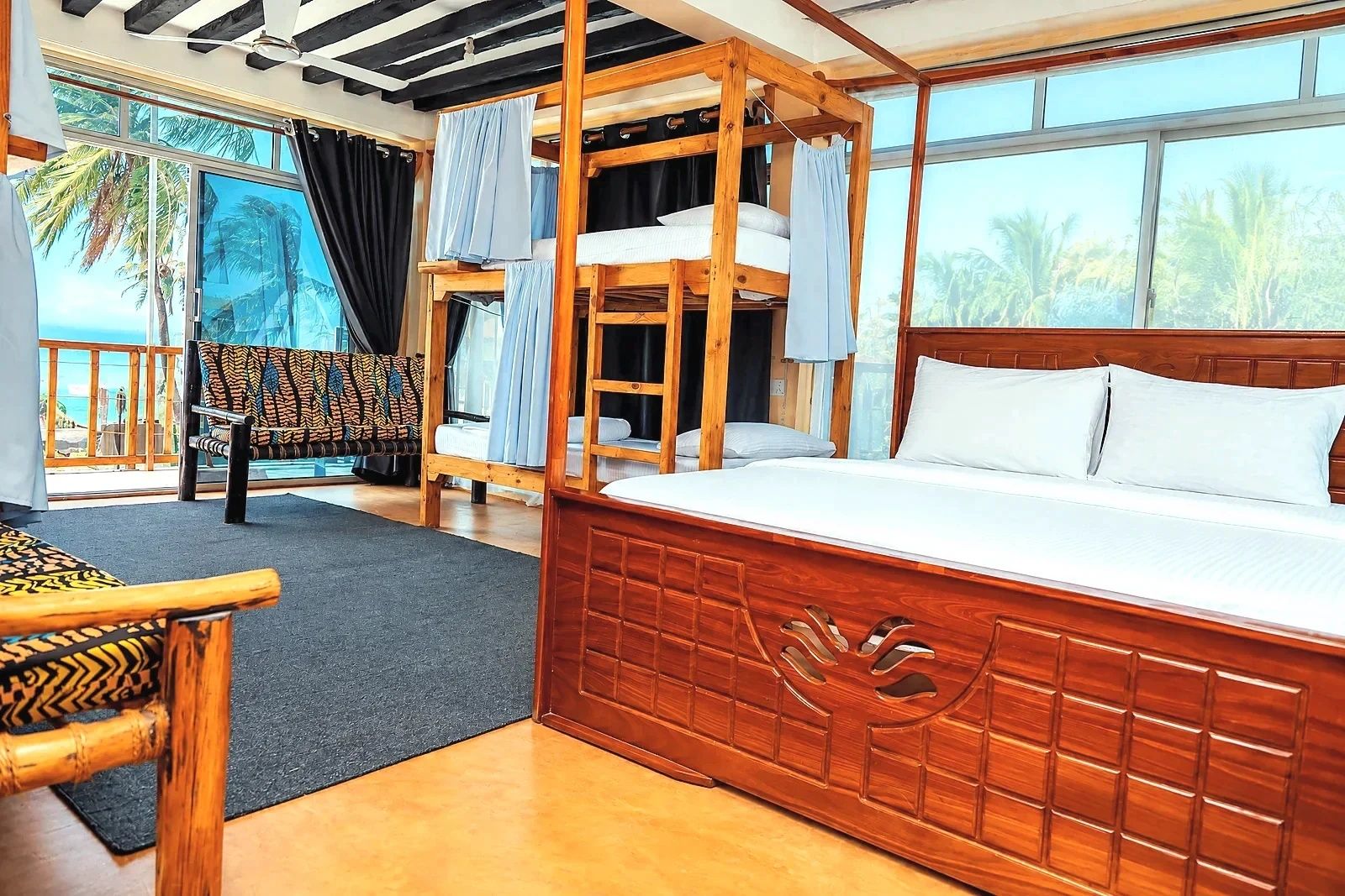 A room with a wooden bunk bed, a sofa, and a view of palm trees.