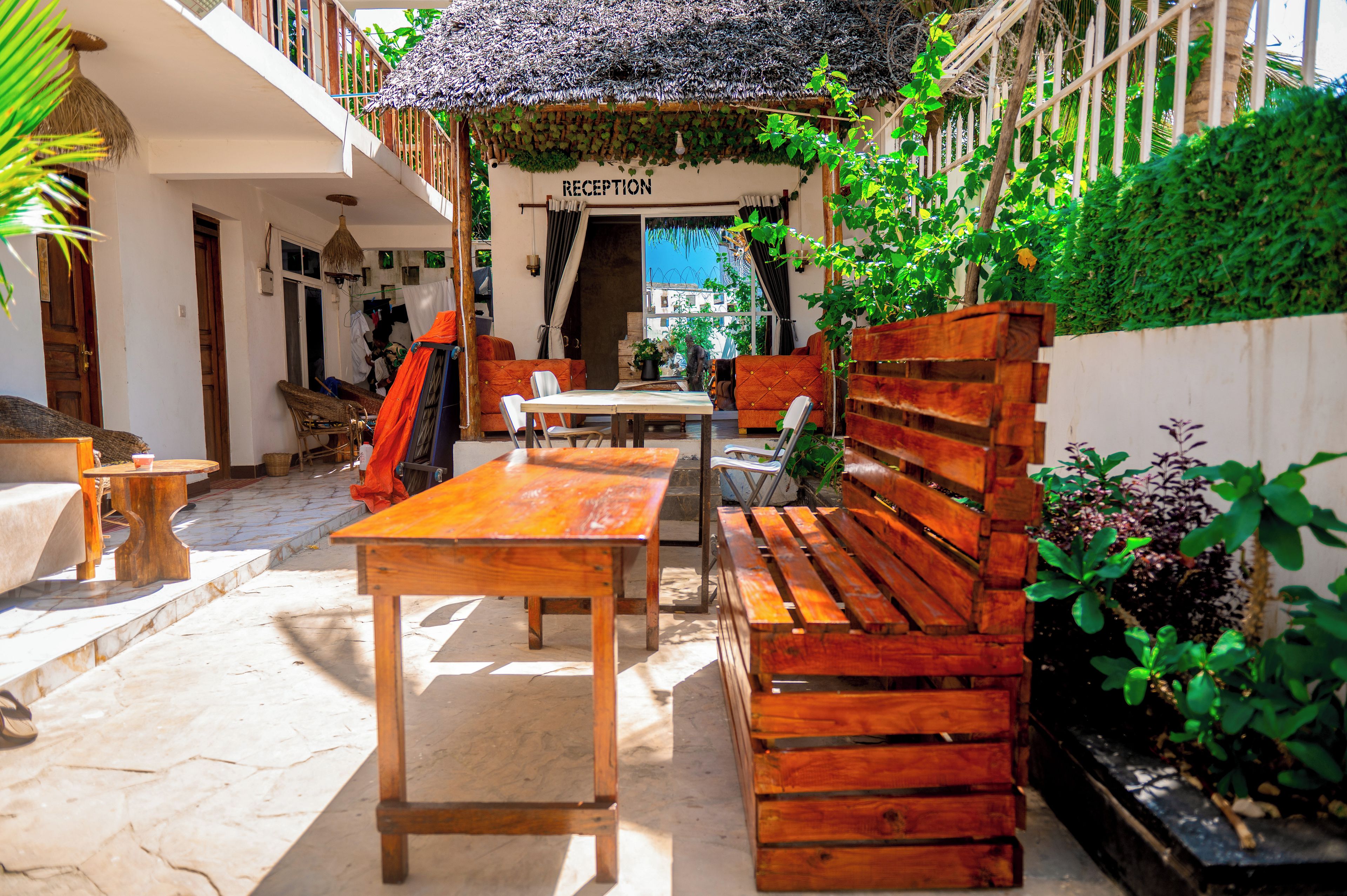 A reception area with a sign, wooden furniture, and a thatched roof.