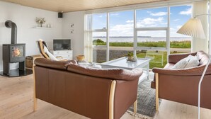 Un salón moderno con un ventanal grande, una chimenea y vistas al exterior.