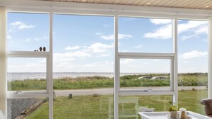 Una habitación con ventanas amplias que ofrecen vista a un área verde y una masa de agua.