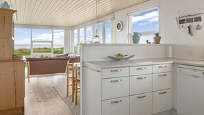 Una cocina moderna con armarios blancos, horno empotrado y un amplio ventanal con vistas panorámicas.