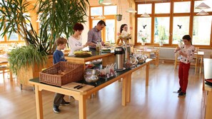 Un café con una larga mesa de madera, cestas y diferentes alimentos.
