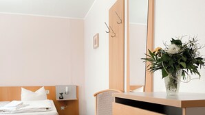 Een hotelkamer met een bed, een stoel, een kaptafel en een spiegel.