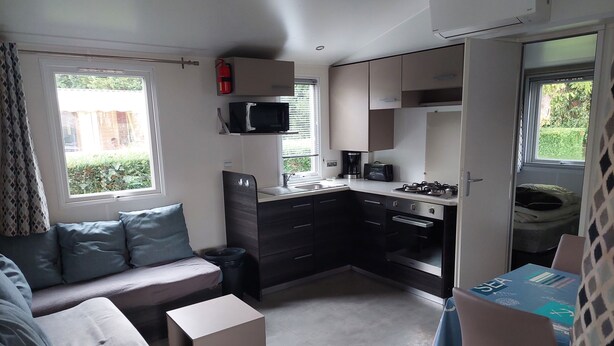 A compact kitchenette with a microwave, stove, and sink. There is a small seating area with a sofa and a table.
