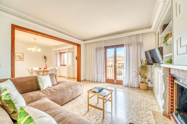 A living room with a sofa, a coffee table, a fireplace, and a TV.