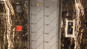 An elevator with a marble wall and a sign indicating a parking area.