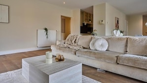 Un salon moderne avec un canapé beige, une table basse et un radiateur.