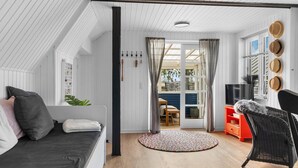 A cozy loft-style room with a bed, a sofa, a wicker chair, and a TV.