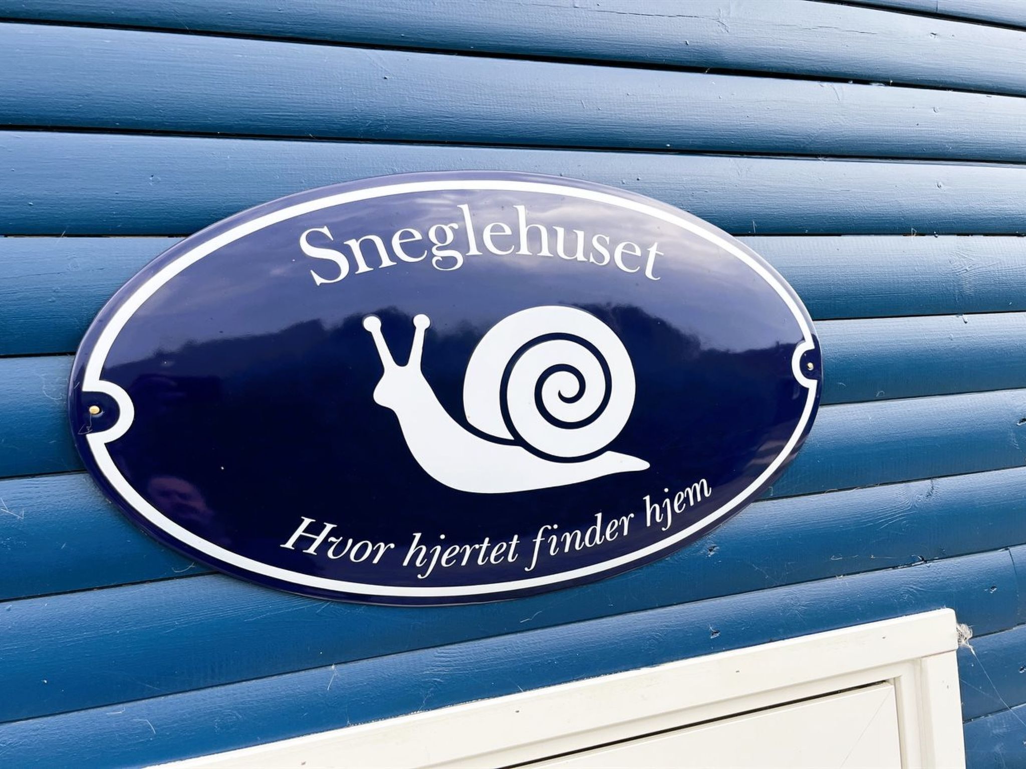 A sign with a snail and the text 'Sneglehuset' and 'Huor hjertet finner hjem'.