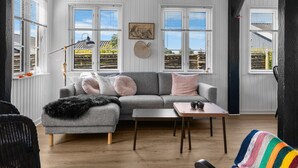 A cozy room with a grey sofa, a small table, and a wicker chair.