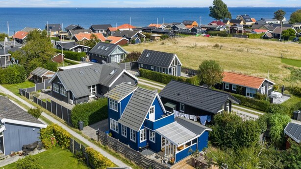 A residential area with houses, a grassy field, and a view of the sea.
